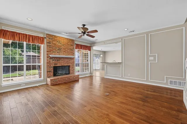 a view of an empty room with wooden floor and a fireplace