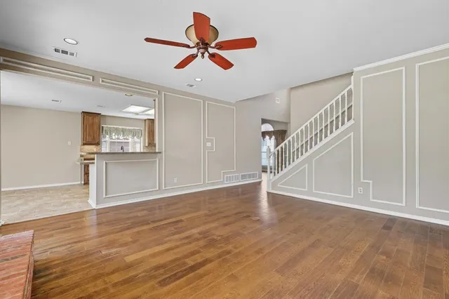 a view of a livingroom with wooden floor a ceiling fan and windows