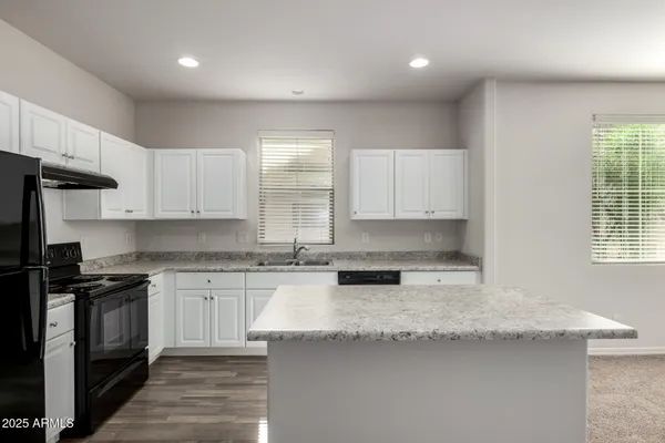 a kitchen with granite countertop a sink a stove and cabinets
