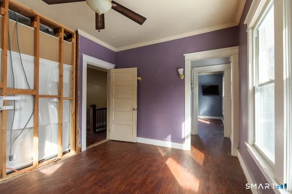 a view of empty room with wooden floor and fan