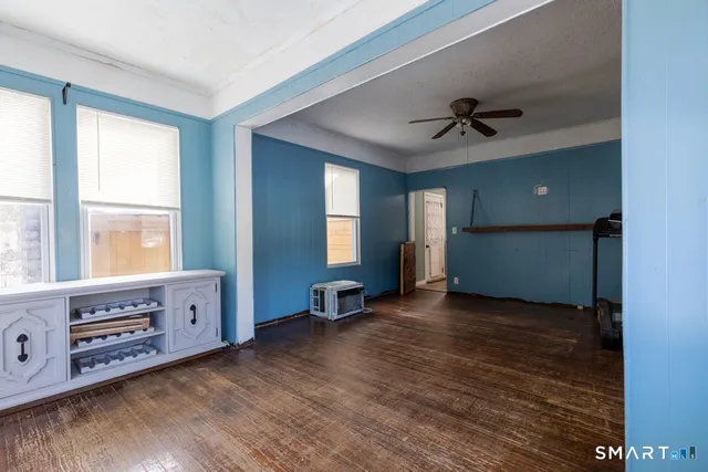 a view of an empty room with window and hardwood floor