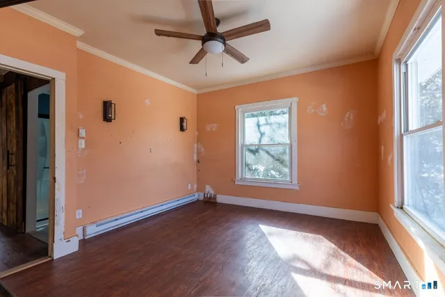 a view of an empty room with a window and wooden floor