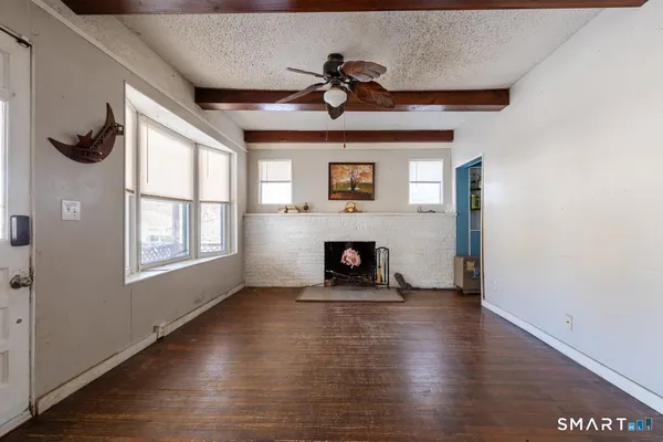 a view of a livingroom with wooden floor a fireplace and window