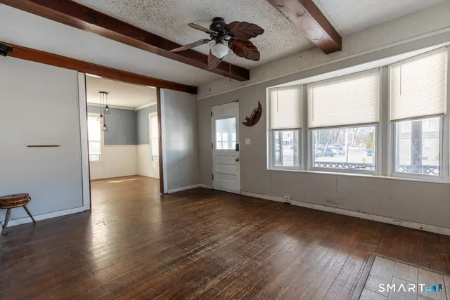 a view of an empty room with a window and wooden floor