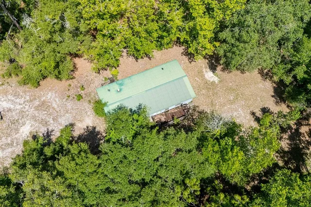 an aerial view of a house with a yard and large trees