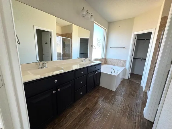 a spacious bathroom with a double vanity sink a large mirror and shower