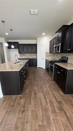 a large kitchen with stainless steel appliances granite countertop a stove a sink dishwasher and a refrigerator