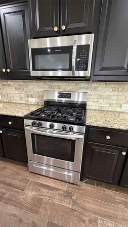 a kitchen with granite countertop a stove and a microwave