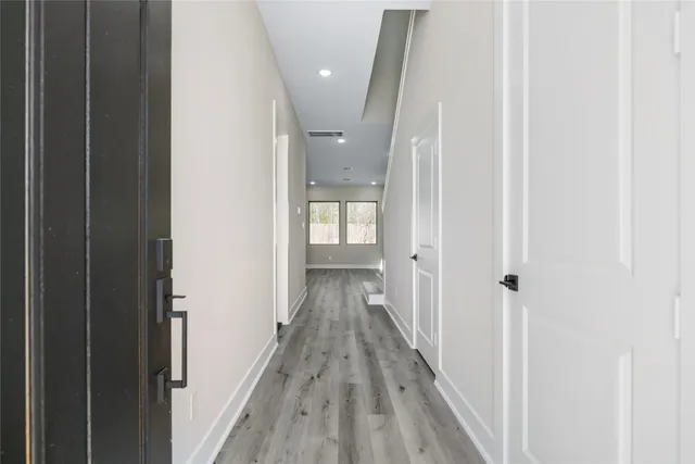 a view of a hallway with wooden floor and a bathroom