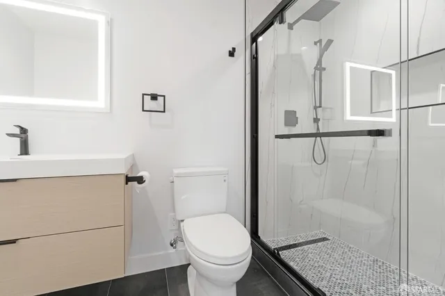 a bathroom with a granite countertop shower a toilet and a sink