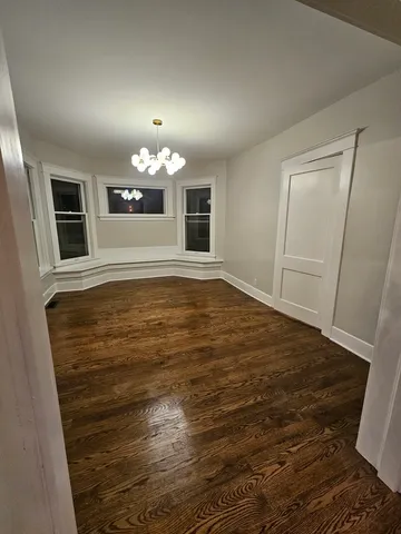 a view of an empty room with chandelier and fireplace