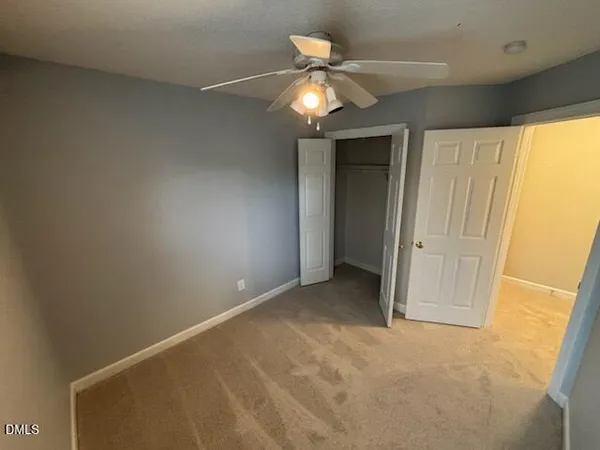 an empty room with a chandelier fan and a large window