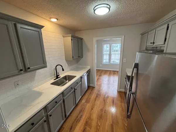 a kitchen with sink a refrigerator and wooden floor