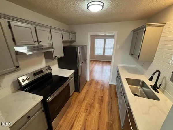 a kitchen with a sink a stove and wooden floor