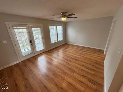 a view of an empty room with wooden floor and a window