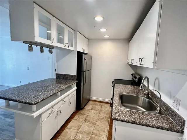 a kitchen with granite countertop a sink and a refrigerator