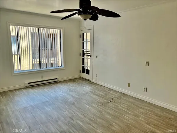a view of an empty room with wooden floor and a window