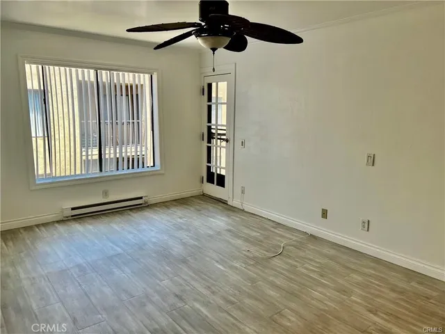 a view of an empty room with wooden floor and a window