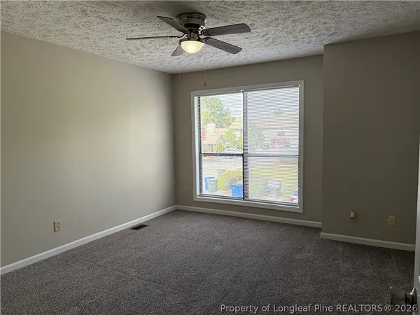 an empty room with a window and a fan