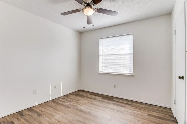an empty room with a window and a fan