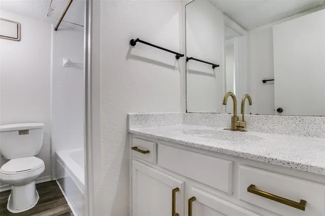a bathroom with a granite countertop sink toilet and mirror