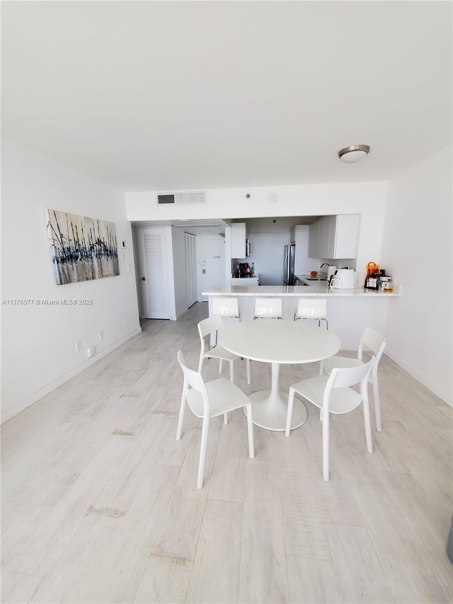 100 Lincoln Road, Unit 1244 Miami Beach, FL 33139 - Photo 18 of 68 a kitchen with a dining table chairs and white cabinets
