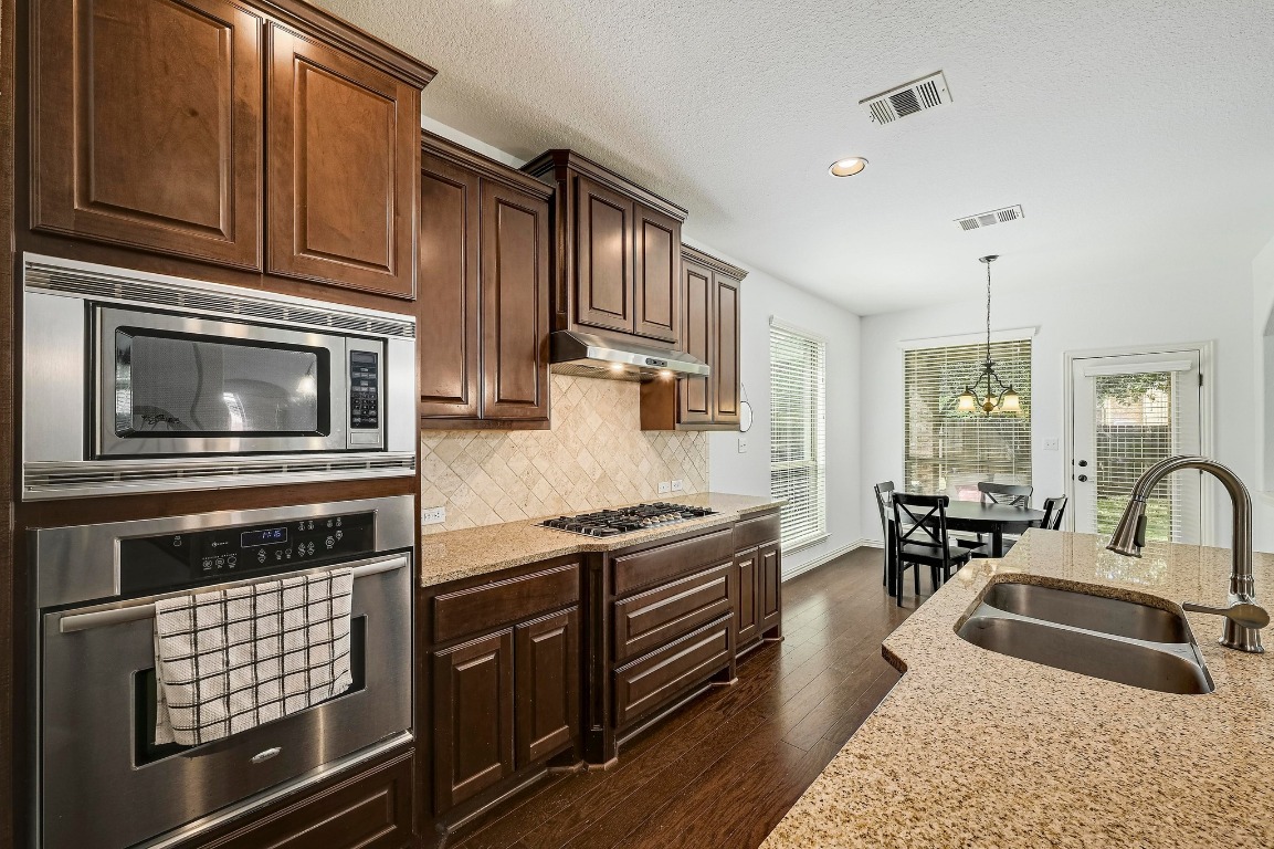 2229 Turtle Mountain Bend Austin, TX 78748 - Photo 11 of 38 a kitchen with granite countertop wooden cabinets a stove and a sink