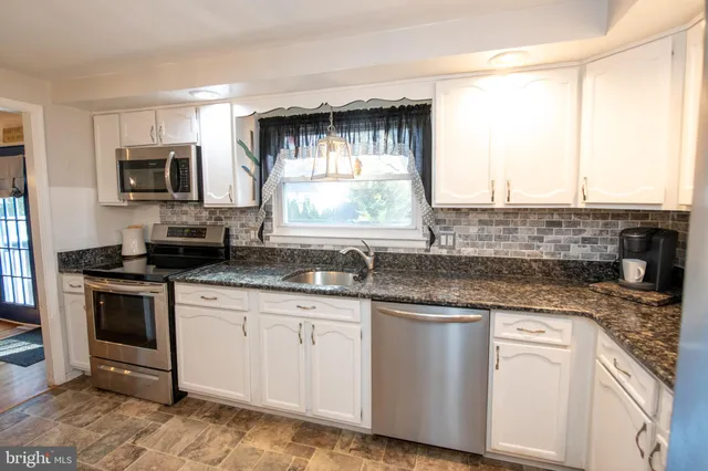 a kitchen with stainless steel appliances granite countertop a sink and a stove