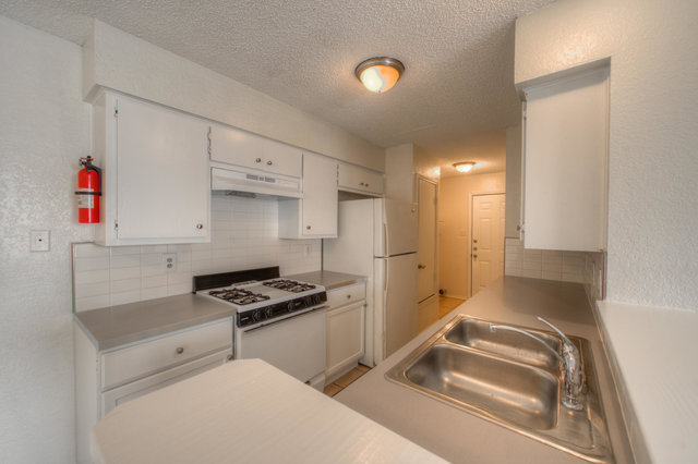 6906 Deep Circle, Unit B Austin, TX 78744 - Photo 11 of 19 Kitchen with a textured wall, white appliances, light countertops, white cabinetry, and tasteful backsplash