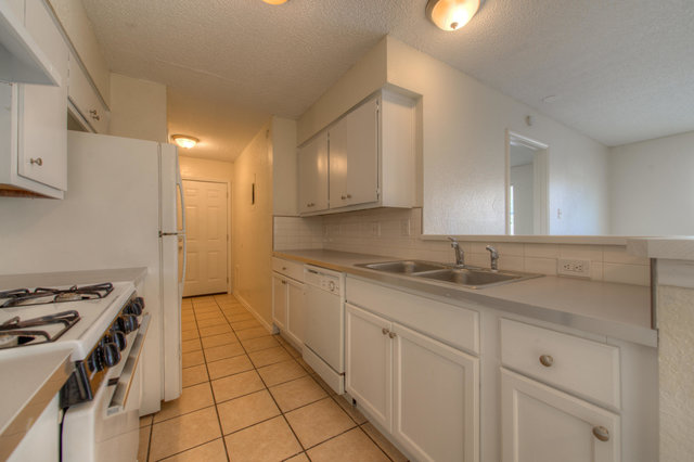 6906 Deep Circle, Unit B Austin, TX 78744 - Photo 12 of 19 Kitchen featuring light countertops, white cabinets, white appliances, light tile patterned floors, and a textured ceiling