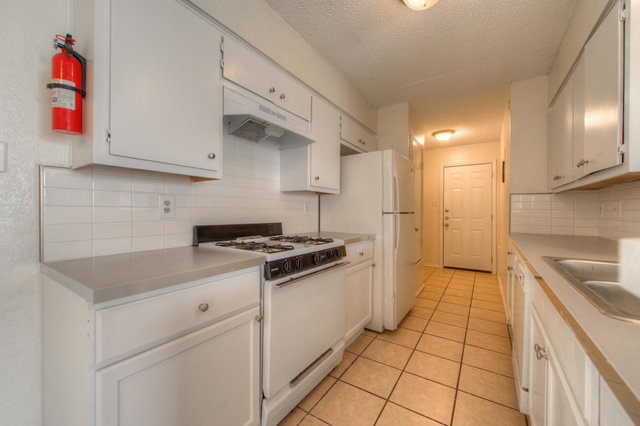6906 Deep Circle, Unit B Austin, TX 78744 - Photo 13 of 19 Kitchen with white appliances, white cabinets, light countertops, a textured ceiling, and light tile patterned floors