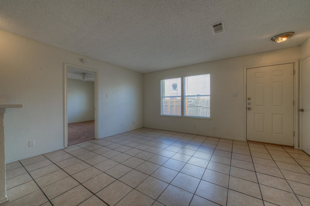 6906 Deep Circle, Unit B Austin, TX 78744 - Photo 5 of 19 Unfurnished living room featuring a textured ceiling and light tile patterned floors