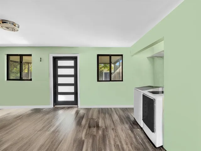 an empty room with wooden floor cabinet and windows