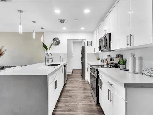 a kitchen with stainless steel appliances granite countertop a sink and dishwasher a stove top oven with white countertops