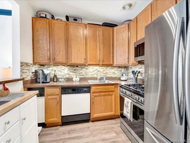 a kitchen with stainless steel appliances granite countertop a refrigerator a stove and a sink