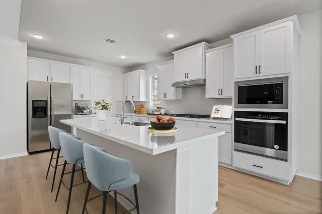 a kitchen with a sink a stove a refrigerator and white cabinets