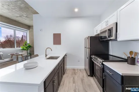 a kitchen with stainless steel appliances a sink a microwave a refrigerator and wooden cabinets