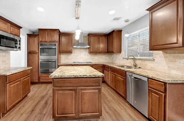 a kitchen with granite countertop stainless steel appliances and wooden cabinets