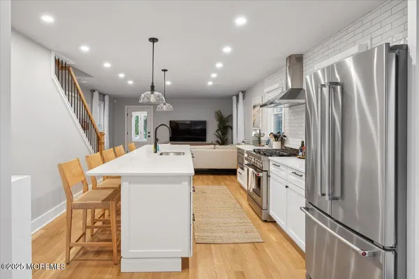 a kitchen with stainless steel appliances kitchen island granite countertop a refrigerator a stove top oven and a sink with cabinets