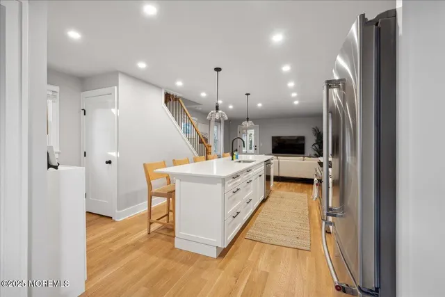 a large white kitchen with stainless steel appliances granite countertop a refrigerator and a wooden floor