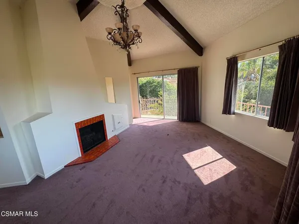 a view of an empty room with a fireplace and windows