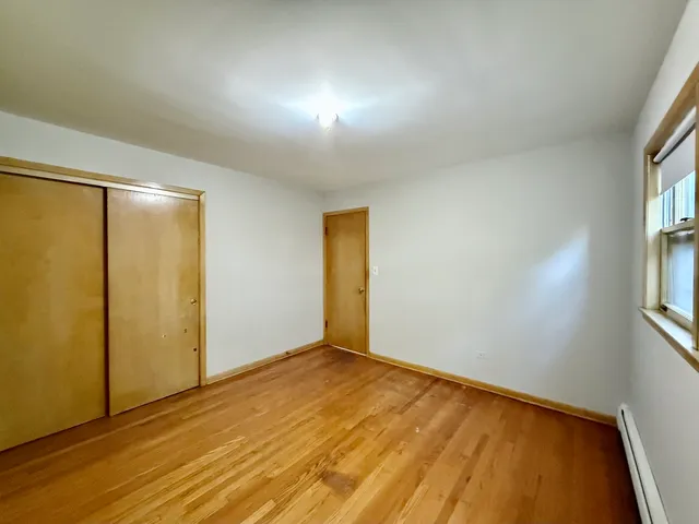 a view of empty room with window and wooden floor