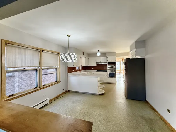 a large kitchen with a refrigerator a sink dishwasher a dining table and chairs