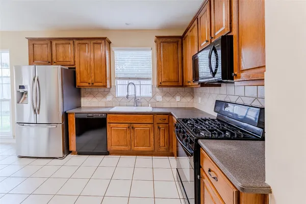 a kitchen with granite countertop a stove a sink and a refrigerator