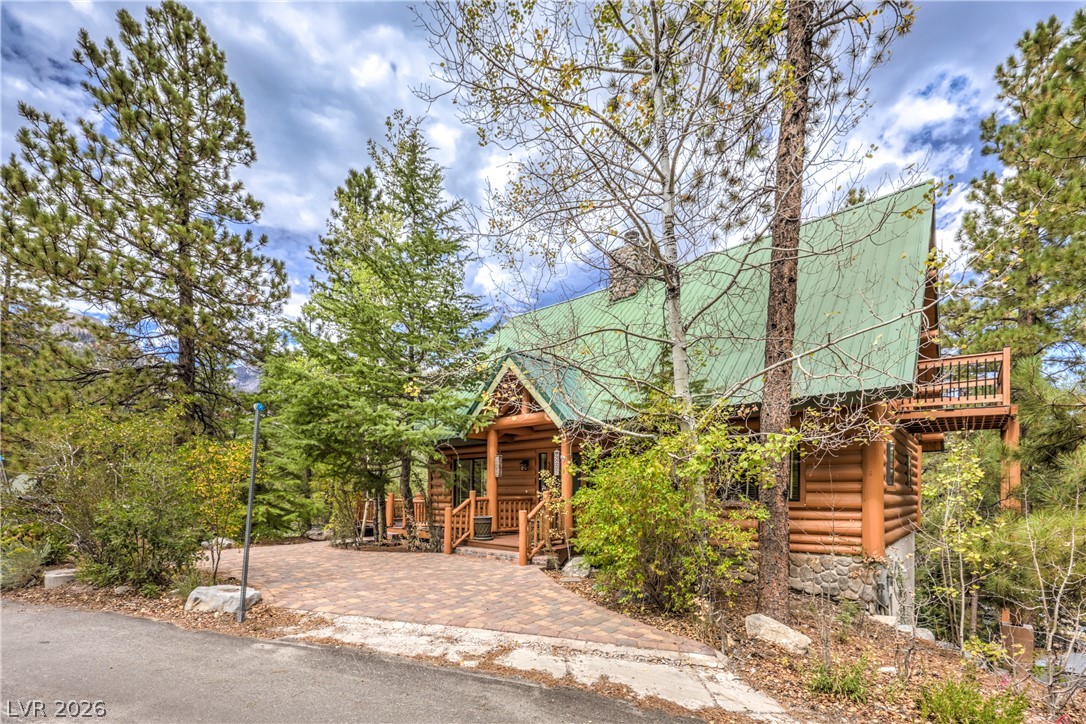 322 Ski Trail Road Mount Charleston, NV 89124 - Photo 1 of 58 Tall pines frame this classic log cabin featuring a paved driveway and metal roof.