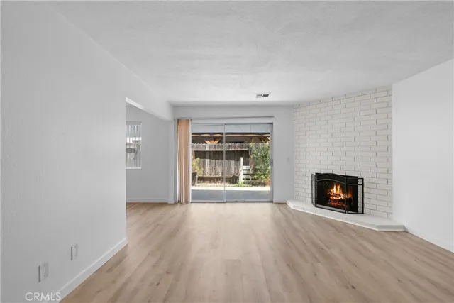 an empty room with wooden floor fireplace and windows
