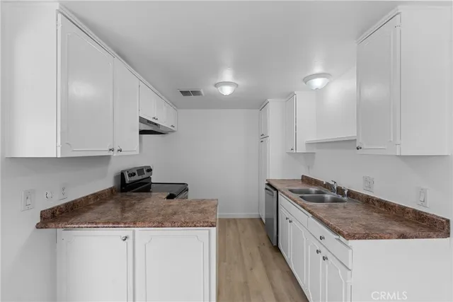 a kitchen with granite countertop a sink a stove and cabinets