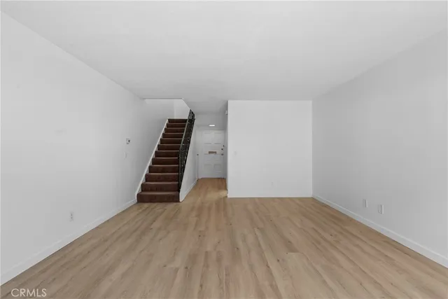 a view of an empty room with wooden floor and stairs