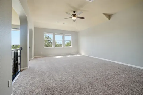 an empty room with windows and ceiling fan