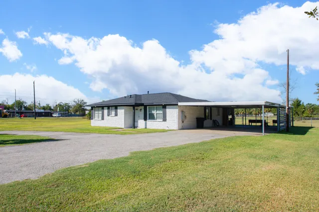 a view of a house with a big yard and large trees
